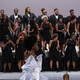 A choir of women in black dresses and men in black tuxes sing and dance during the Pyer Moss show